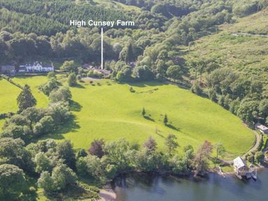 A green field with scattered trees near a body of water and houses marked as High Cunsey Farm in Far Sawrey