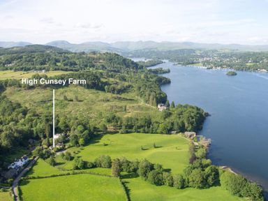 Aerial view of farmland and a large body of water with hills in the background at High Cunsey Farm Far Sawrey