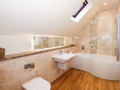 A bathroom with a toilet sink and bathtub with a glass shower screen at Squirrel Bank in Ambleside