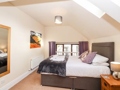 A bedroom with a double bed beside a wooden nightstand and a wall mirror at Squirrel Bank in Ambleside
