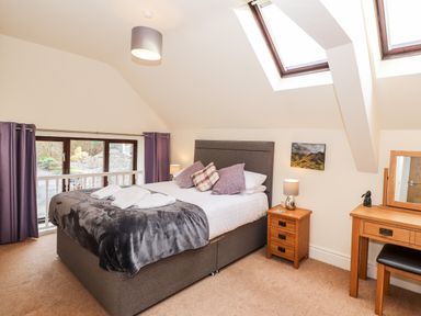 A bedroom with a double bed bedside tables a dressing table and skylight windows at Squirrel Bank Ambleside