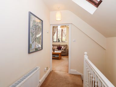 A hallway with a framed map on the wall and a radiator leading to a living room with a sofa and coffee table at Squirrel Bank in Ambleside