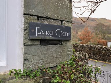A stone wall with a sign reading Fairy Glen near a driveway and trees at Fairy Glen in Grasmere near Ambleside