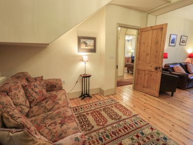 A sitting area with a floral sofa and a patterned rug next to a wooden door at Fairy Glen in Grasmere near Ambleside