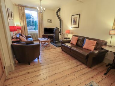 A living room with leather sofas a coffee table a wood stove and a television at Fairy Glen in Grasmere near Ambleside