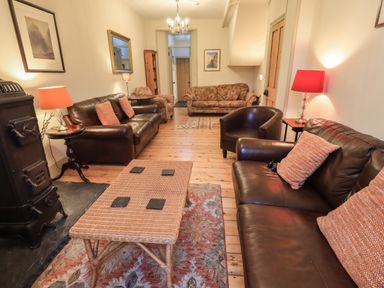 A living room with brown leather sofas armchairs and a wicker coffee table at Fairy Glen in Grasmere near Ambleside