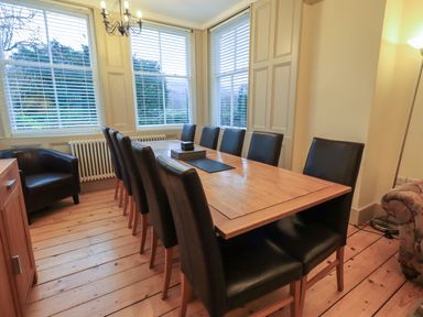 A dining room with a wooden table and black chairs near large windows at Fairy Glen in Grasmere near Ambleside