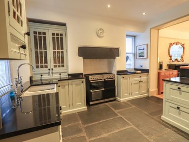 A kitchen with cabinets a stove a sink and a window at Fairy Glen in Grasmere near Ambleside