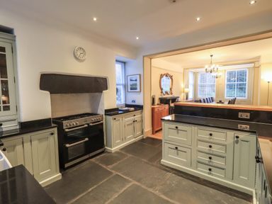 A kitchen with cabinets and a stove opening to a dining room at Fairy Glen in Grasmere near Ambleside