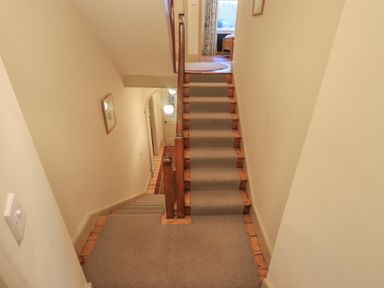 A carpeted staircase with wooden banisters and beige walls at Fairy Glen in Grasmere near Ambleside