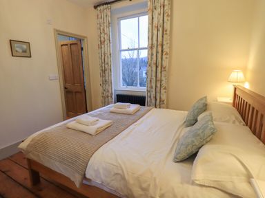 A bedroom with a double bed two folded towels by the window and a bedside lamp at Fairy Glen in Grasmere near Ambleside