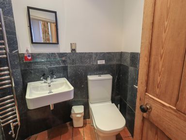 A bathroom with a toilet sink mirror and wooden door at Fairy Glen in Grasmere near Ambleside