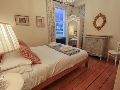 A bedroom with a wooden bed with pillows and towels a dresser with a mirror a standing wardrobe and a chair at Fairy Glen in Grasmere near Ambleside