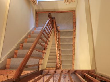 A stairway with light grey carpet and wooden banisters at Fairy Glen in Grasmere near Ambleside