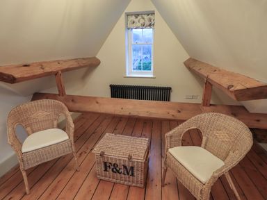 A small attic room with two wicker chairs and a wicker basket on wooden floorboards at Fairy Glen in Grasmere near Ambleside