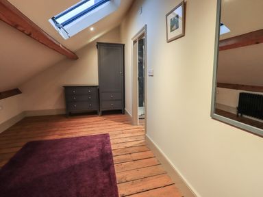 An attic room with wooden flooring dark gray drawers skylight window and a purple rug at Fairy Glen in Grasmere near Ambleside