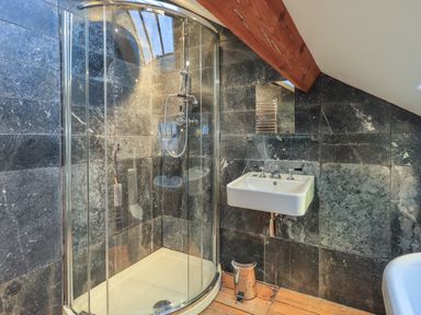 A bathroom with a corner shower cubicle a wall-mounted sink and a wooden beam at Fairy Glen in Grasmere near Ambleside
