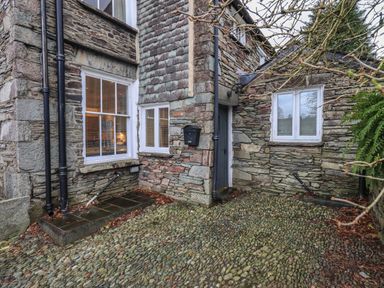 A stone exterior corner of a building with windows and a door at Fairy Glen in Grasmere near Ambleside