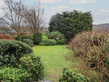 A garden area with grass lawn shrubs and trees at Fairy Glen in Grasmere near Ambleside