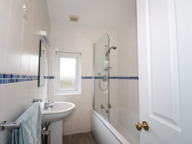 A bathroom with a bathtub a shower a sink and a towel hanging at Larch Cottage in Hawkshead