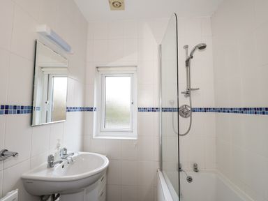 A bathroom with a sink mirror window bathtub and shower at Larch Cottage in Hawkshead