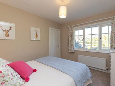 A bedroom with a bed near a window two framed animal prints on the wall and a radiator at Crozier Cottage in Grasmere