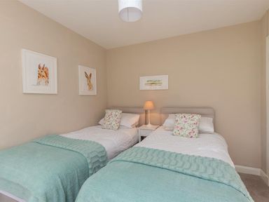 A bedroom with two single beds with blue throws and floral pillows at Crozier Cottage in Grasmere