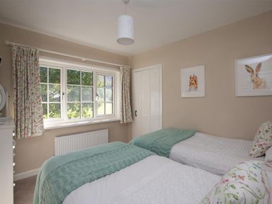 A bedroom with two single beds and floral curtains at Crozier Cottage in Grasmere