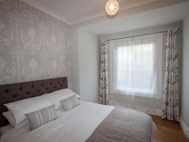 A bedroom with a bed pillows and a window with curtains at Waterside in Ambleside