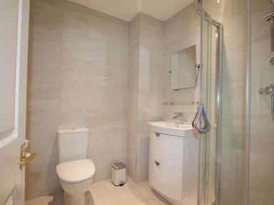 A bathroom with a toilet sink with mirror and glass shower enclosure at Waterside in Ambleside