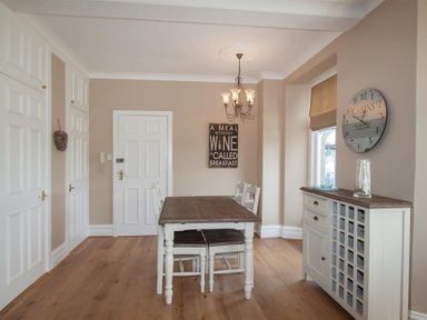 A dining room with a wooden table and chairs a chandelier a wall clock and a cupboard at Waterside in Ambleside