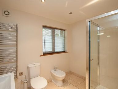 A bathroom with a toilet bidet glass shower and window blinds at Dancing Beck Cottage Millbeck