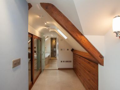 A bathroom with wooden beams wardrobes and a glass shower at Dancing Beck Cottage in Millbeck