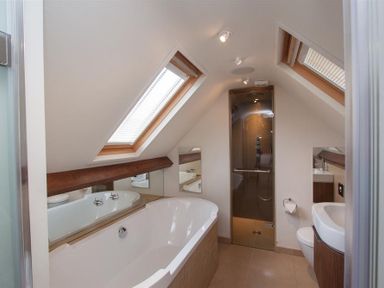 A bathroom with a bathtub shower sink toilet and skylight windows at Dancing Beck Cottage Millbeck