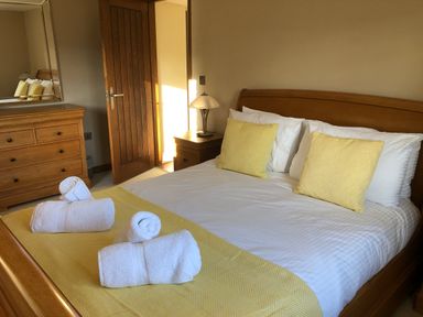 A bedroom with a bed, dresser, and door at Dancing Beck Cottage in Millbeck