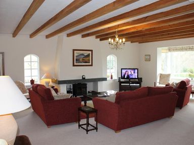 A living room with wooden ceiling beams red sofas a fireplace and a television at Bandol in Braithwaite