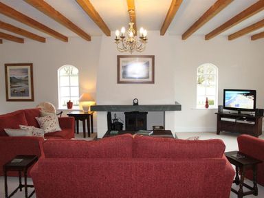 A living room with two red sofas a fireplace and a television at Bandol in Braithwaite