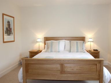 A bedroom with a wooden bed and bedside tables with lamps at Bandol in Braithwaite