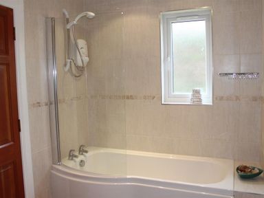A bathroom with a bathtub shower combination under a window at Bandol in Braithwaite