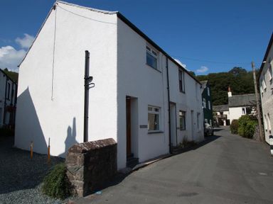 A street with white houses and stone walls under a blue sky at Gable End in Braithwaite