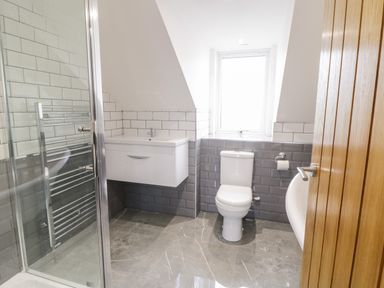 A bathroom with a shower, sink, toilet, and window at Meadow View in Tyn-y-Gongl near Benllech