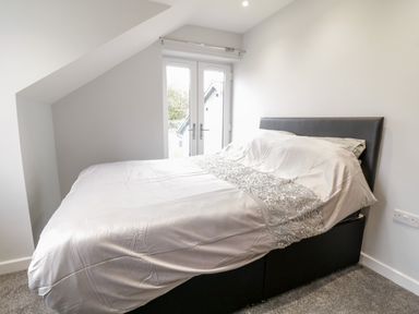 A bedroom with a bed near glass doors at Meadow View in Tyn-y-Gongl near Benllech