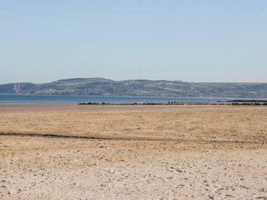 A beach area with water and hills at Meadow View Benllech