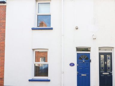 Exterior of a white building with two blue doors and two windows at South Harbour Cottage in Weymouth