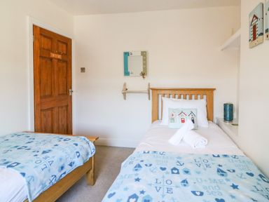 A bedroom with two single beds wooden door and wall decorations at South Harbour Cottage in Weymouth