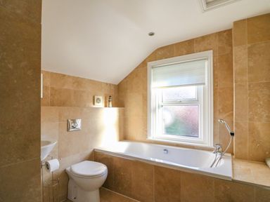 A bathroom with a toilet bathtub sink and window at South Harbour Cottage in Weymouth