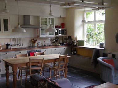 A kitchen with wooden table and chairs stove oven and hanging lights at Thomas Cottage in Hartsop