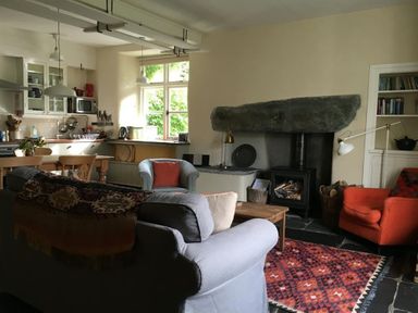 A living room with seating and a fireplace near a kitchen at Thomas Cottage in Hartsop
