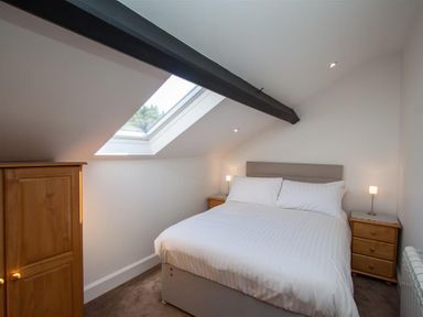 A bedroom with a double bed two bedside tables with lamps a wooden wardrobe and a skylight window at Robins Nest in Coniston