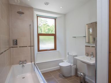 A bathroom with a bathtub shower toilet sink and a window at Robins Nest in Coniston